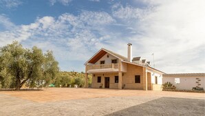 A two-story house with a balcony, a chimney, and a paved courtyard. - Amazing home in Lucena (Lucena)