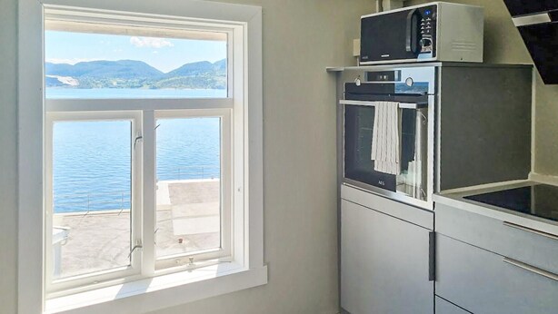 Een keuken met uitzicht op een meer en bergen, met een magnetron, oven en spoelbak.