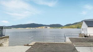Een pand aan het water met een aanlegsteiger, een klein gebouw en een uitzicht op bergen in de verte.