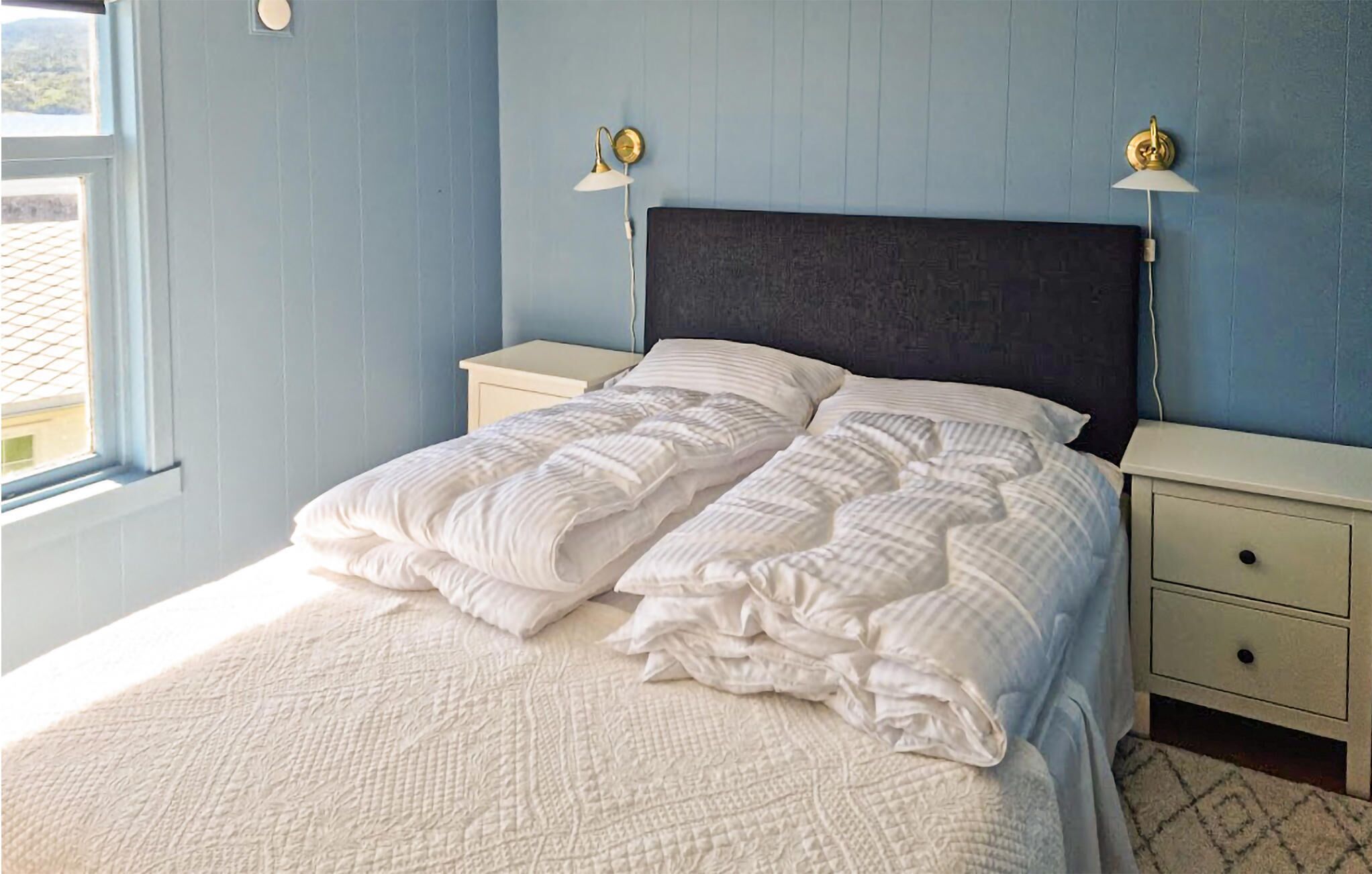 Een slaapkamer met een bed, twee nachtkastjes en twee wandlampen.