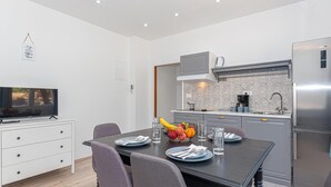 A modern kitchen with grey cabinets, a stainless steel refrigerator, and a dining area with a table set for two. - Nice apartment in Danilo with WiFi (Danilo)