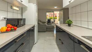 A modern kitchen with a refrigerator, microwave, and a dining area with a sofa and table. - Beautiful home in Rosini (Rosini)