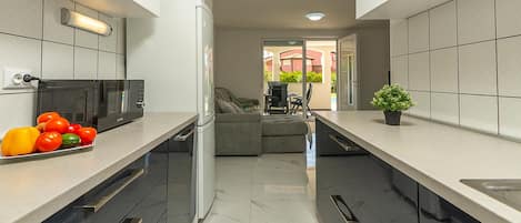 A modern kitchen with a refrigerator, microwave, and a dining area with a sofa and table.