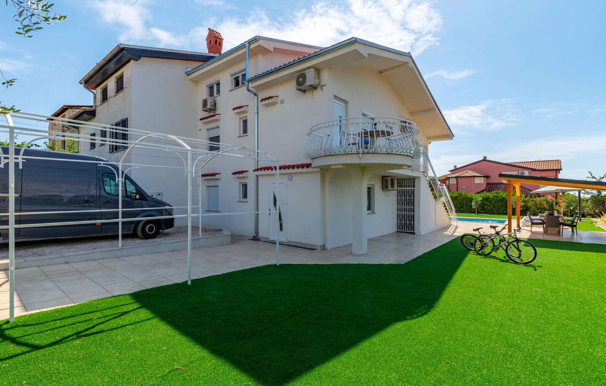 A two-story house with a balcony, a covered patio, and a swimming pool.