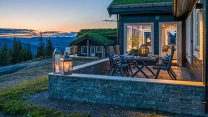 En mysig utomhusplats med sittplatser, stenmurar, en lykta och utsikt över bergen.