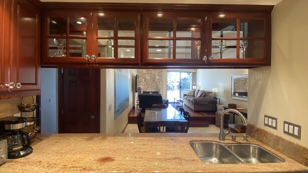 A kitchen with granite countertops, stainless steel sink, wooden cabinets, and a dishwasher. - Luxurious • Upscale • Open Concept • Elegant • Beautifully Maintained (Huntington Beach)