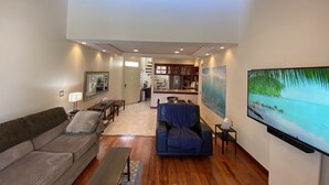 A spacious living area with a high ceiling, a kitchen in the background, and a large painting on the wall. - Luxurious • Upscale • Open Concept • Elegant • Beautifully Maintained (Huntington Beach)
