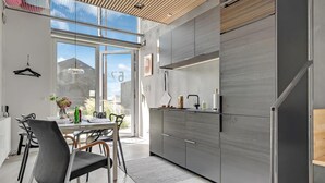 Et moderne køkken med et stort vindue, et spiseområde med stole og en køkkenbordplade med vask og skabe.