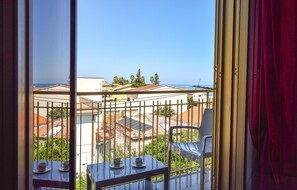 Ein Balkon mit Tisch und Stühlen, mit Blick auf eine Wohngegend mit Häusern und klarem Himmel.