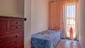 A bedroom with a bed, a wooden dresser, and a window with sheer curtains. - Gorgeous apartment in Marina di Caronia with WiFi (Marina di Caronia)