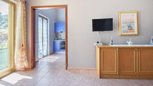 A room with a TV mounted on the wall, a wooden cabinet, and a painting. - Gorgeous apartment in Marina di Caronia with WiFi (Marina di Caronia)
