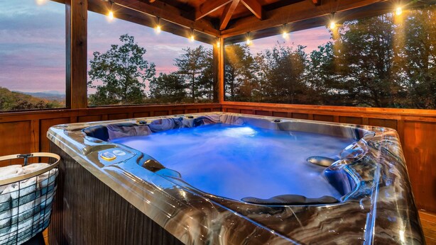 A hot tub with a wooden deck and a view of trees and hills. - Sunset Mountain Views • 3 King Suites • Hot Tub • Game Room • 8 mi to Dollywood (Sevierville)