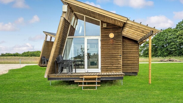 Une cabane en bois avec une porte en verre, un espace salon extérieur et une petite terrasse.