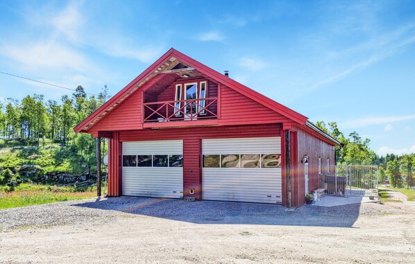 Une grange rouge avec un balcon et deux portes de garage.
