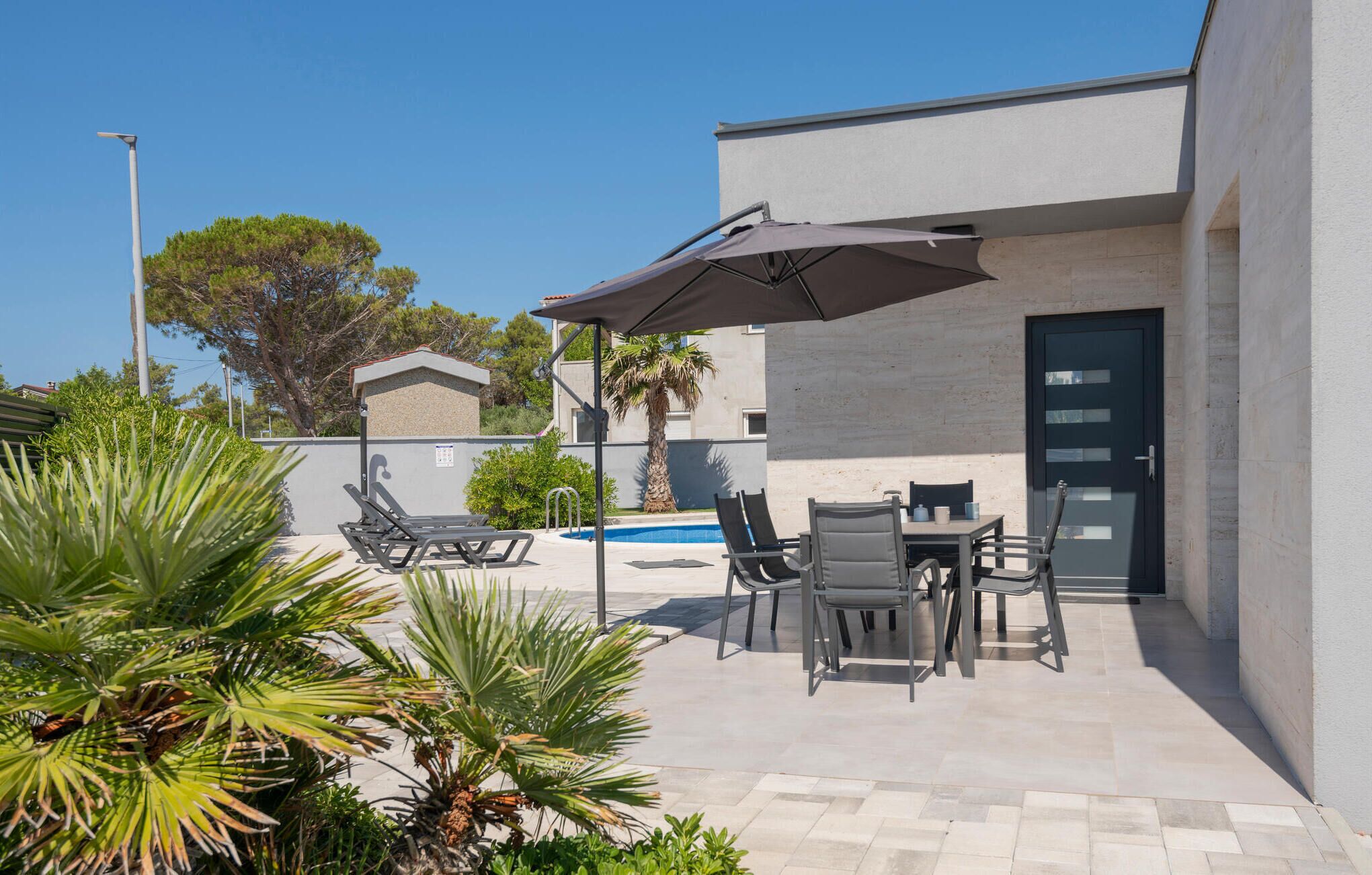 Eine Terrasse mit Sitzgelegenheiten im Freien, einem Pool und einem Gebäude mit Tür und Fenstern.