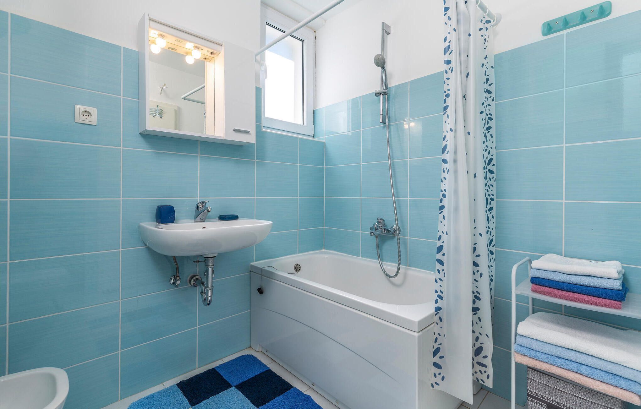 Une salle de bain équipée d’un lavabo, d’un miroir, d’une douche et d’un porte-serviettes avec des serviettes.