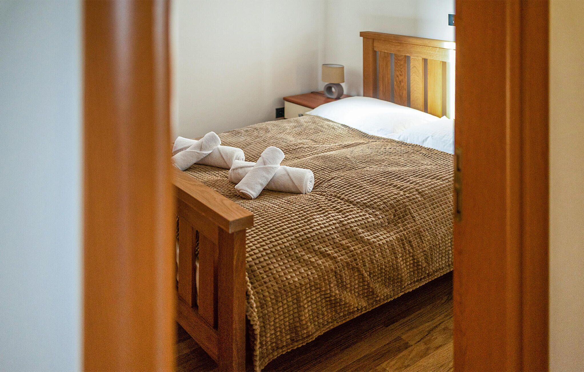 A neatly made bed with a textured blanket and two white towels folded at the foot.