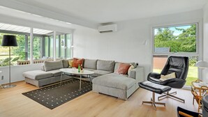 Ein modernes Wohnzimmer mit einem grauen Ecksofa, einem schwarzen Ledersessel und einem runden Couchtisch.