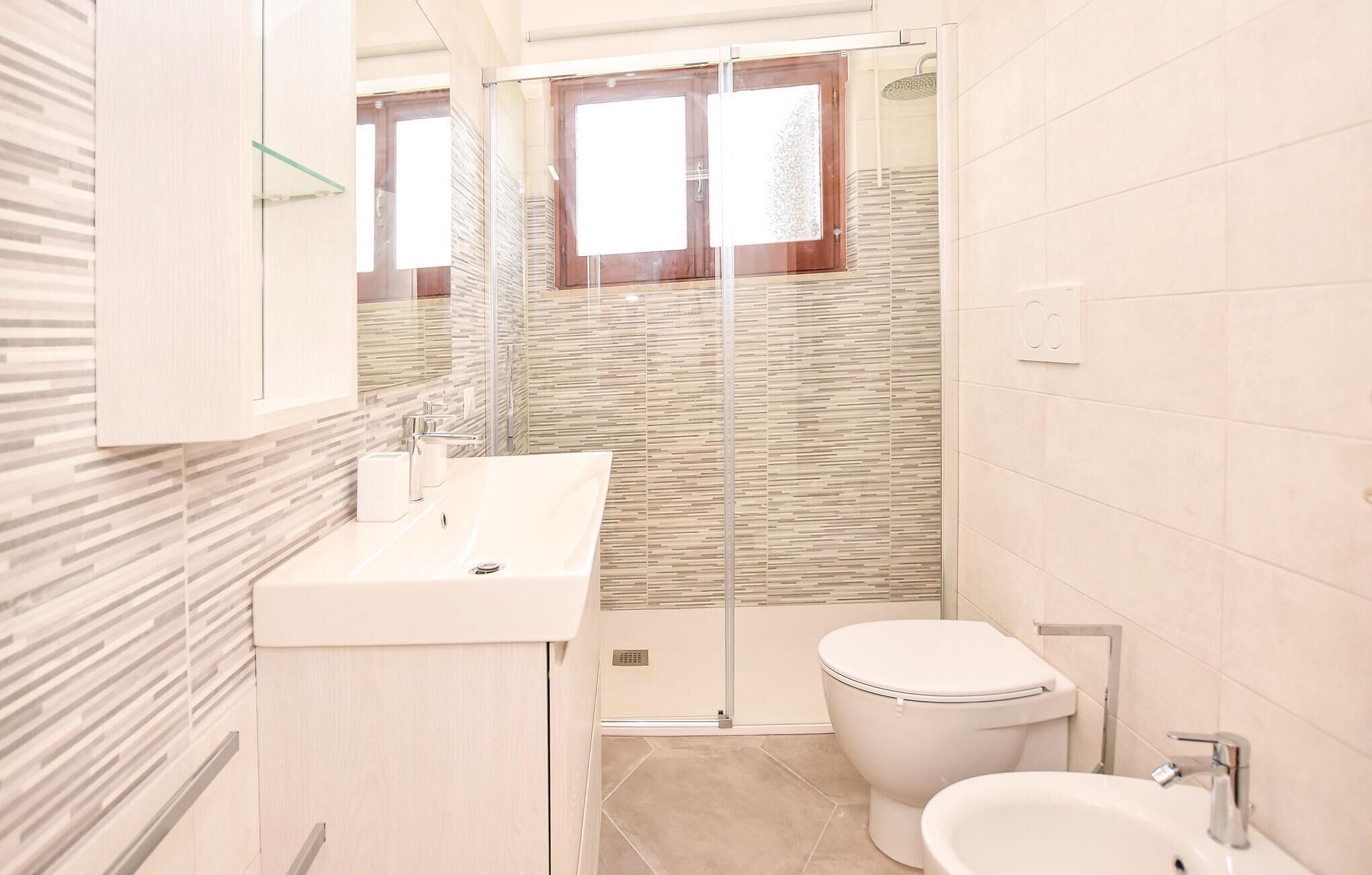 Une salle de bain moderne avec une douche à parois de verre, un lavabo blanc et des toilettes.