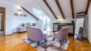 A spacious loft with high ceilings, exposed wooden beams, a large window, a sofa, two armchairs, a small table, and a cabinet. - Amazing home in Vrlika with house a mountain view (Vrlika)