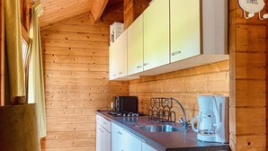 Une cuisine de taille réduite avec des murs en bois, un évier en acier inoxydable, une machine à café et une cuisinière.