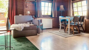 Une pièce confortable avec un canapé, une petite table, une table à manger avec des chaises et un radiateur.
