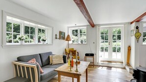 A cozy living room with a grey sofa, wooden coffee table, and a fireplace. - 2 bedroom beautiful home in Gudhjem (Gudhjem)