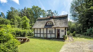 A traditional thatched-roof house with a wooden exterior, a small garden, and a picnic table. - 2 bedroom beautiful home in Gudhjem (Gudhjem)