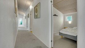 Un couloir menant à une chambre à coucher, qui contient un lit, une fenêtre et une porte.