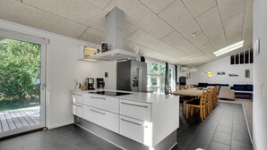 Une cuisine moderne dotée d’un grand îlot central, d’appareils électroménagers intégrés et d’un coin repas avec une longue table et des chaises.
