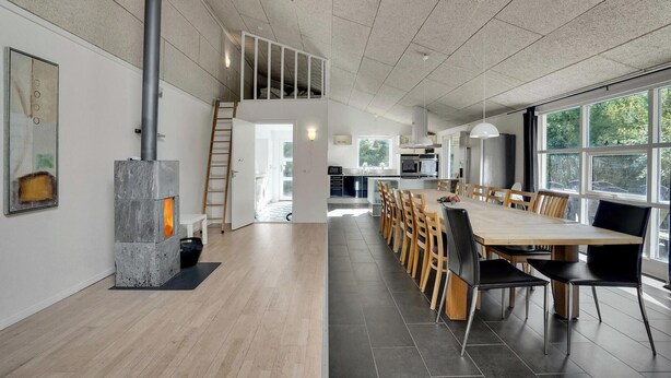 Une cuisine spacieuse dotée d’un îlot central, d’un coin repas avec des chaises en bois et d’une grande fenêtre qui laisse entrer la lumière naturelle.