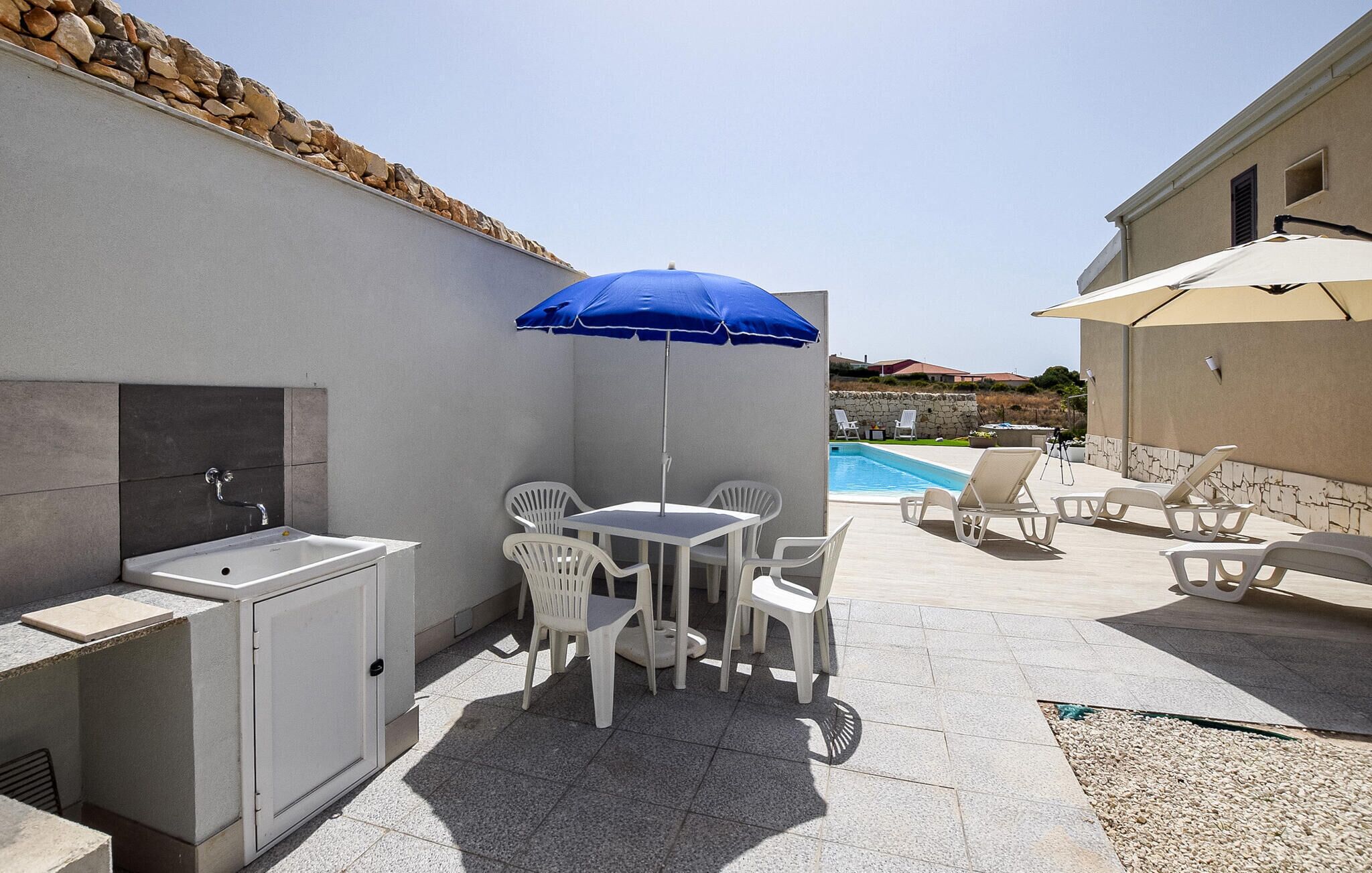 A patio area with a pool, outdoor seating, and a sink.