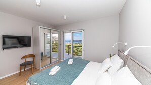 A bedroom with a bed, a chair, a TV, and a balcony with a view. - Lovely home in Kastel Stafilic (Kastel Stafilic)