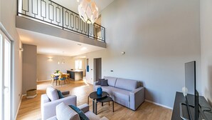 A spacious living area with a sofa set, a coffee table, and a TV. There is a balcony with a railing and a dining area in the background. - Lovely home in Kastel Stafilic (Kastel Stafilic)