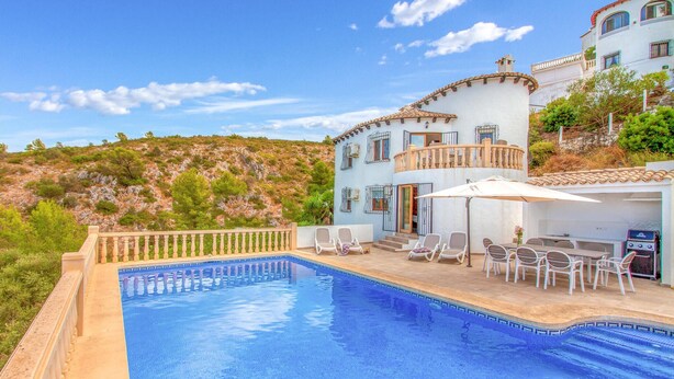 A poolside area with a pool, outdoor seating, and a building with a balcony. - Stunning home in Pedreguer (Pedreguer)