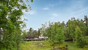 A modern house with a large deck, surrounded by lush greenery and trees.