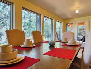 A dining area with a wooden table, red placemats, and white plates.