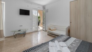 A bedroom with a bed, a crib, a glass table, and a TV on the wall. - Gorgeous apartment in Crikvenica with WiFi (Crikvenica)