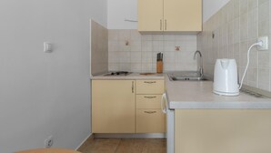 Una pequeña kitchenette con un lavamanos, una tetera y un juego de cuchillos.