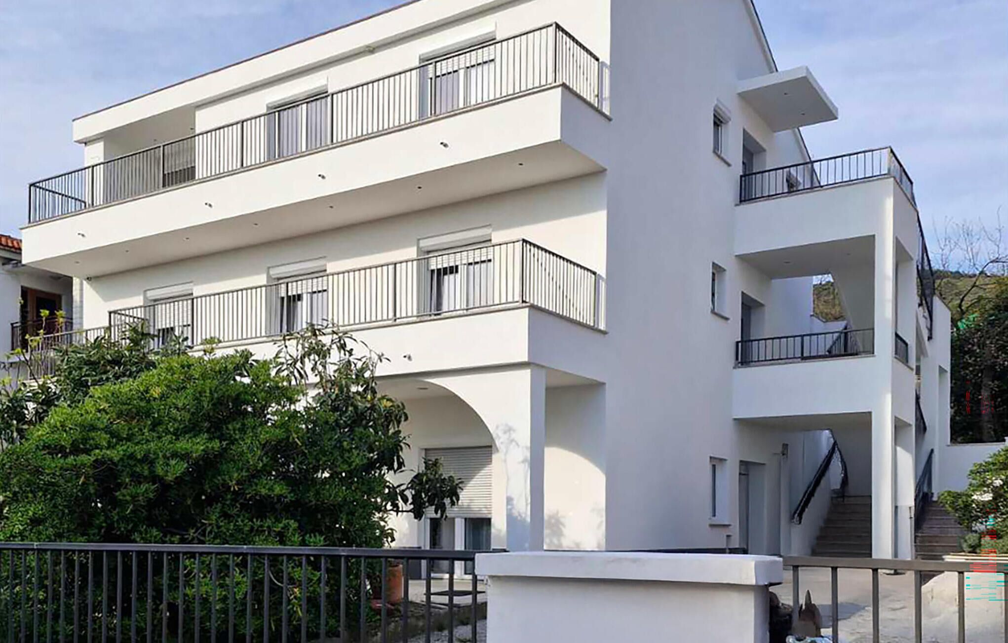 A modern multi-story building with balconies and a staircase.