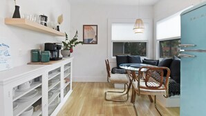 A compact kitchen with a dining area, featuring a wooden table, chairs, and a blue refrigerator. - Historic Bungalow Between Beach & Downtown (St. Augustine)