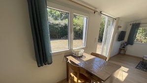 Uma área de refeições com mesa, cadeiras, janelas amplas e vista para o exterior.