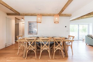 Un comedor con una mesa de madera, seis sillas y dos lámparas colgantes.
