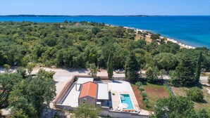 Eine Villa mit Swimmingpool, umgeben von üppiger Vegetation und einem Strand.