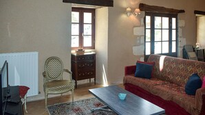Una sala de estar acogedora con un sofá rojo, una silla de madera, una mesita y un radiador.