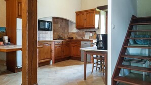 Una cocina con armarios de madera, un microondas, una cafetera y una escalera.
