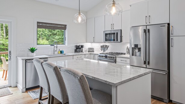 A modern kitchen with a central island, stainless steel appliances, and pendant lighting.