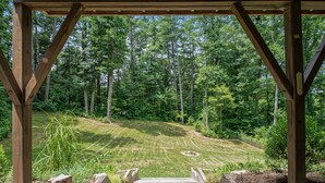 A wooden staircase leading to a covered area with a view of a forested landscape.