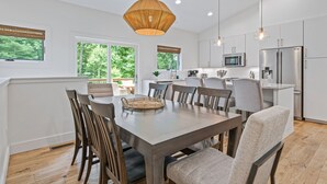 A modern kitchen with white cabinets, stainless steel appliances, and a dining area with a wooden table and chairs.