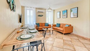 A dining area with a wooden table set for four, two orange leather sofas, and a ceiling fan. - Amazing home in Sanary-sur-Mer with WiFi (Sanary-sur-Mer)